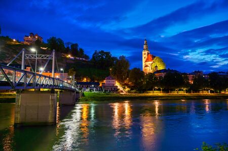 A view of Salzburg, Austria along the Salzach River at night.の写真素材