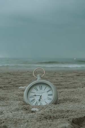 Clock on the beach sand in verticalの写真素材