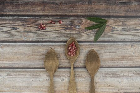 composition of three spoons of wood with pomegranate nuggets on vintage wooden backgroundの写真素材