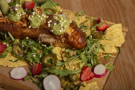 Brunch. First flat sandwich filled with chicken mix, pico de gallo, tortilla chips, guacamole, arugula, strawberries, radishes and nachos on a wooden board.の写真素材