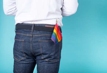Man from the back with LGBT pennant in the pocket of jeans on a blue background.の写真素材
