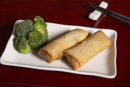 Spring roll with broccoli on wooden table.