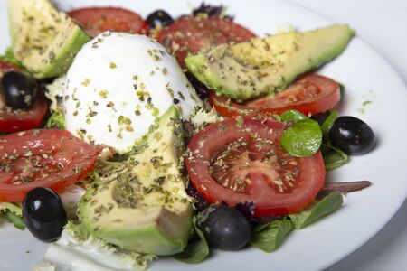 Mozzarella salad with avocado tomatoes and black olives. Isolated image. Selective focus.の写真素材