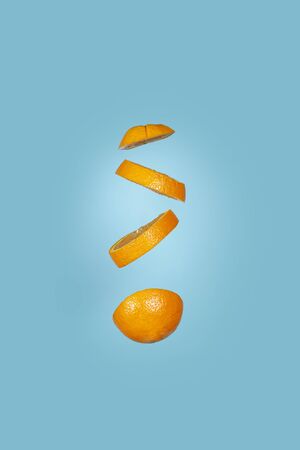 Creative concept with flying orange.Sliced orange isolated on blue background. Vertical imageの写真素材