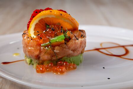 Close up of salmon and avocado tartare served with wakame seaweed, strawberries and lumpfish roe. Asian foodの写真素材