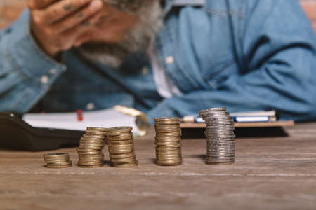 Man at desk in denim shirt holding head and worrying about money.の写真素材