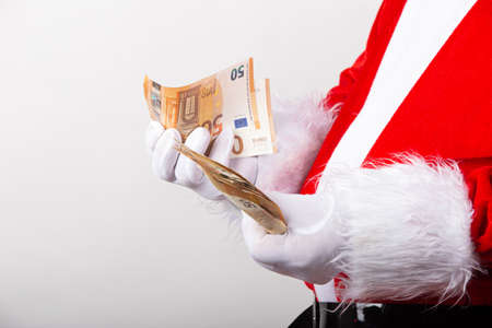 Santa counting fifty Euro banknotes in profile to camera isolated on white background.の写真素材