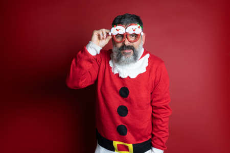 Studio portrait of a bearded man in tight santa claus hat and christmas clothes. Close up, copy space for text, isolate background.の写真素材