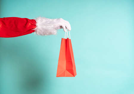 Santa Claus hand holding a red gift bag on blue background.の写真素材