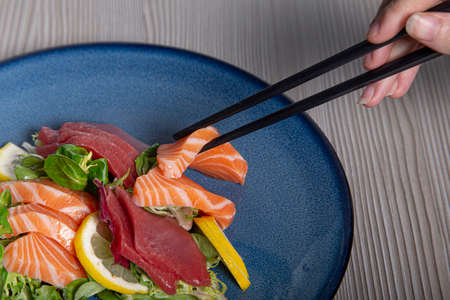 Eat sashimi with closed chopsticks. Raw Fish. Isolated image with copy spaceの写真素材