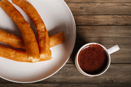 Batons with chocolate on wooden background. Typical Spanish appetizer like a fried dough. Image...