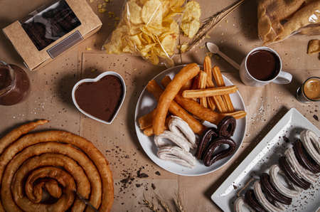 Variety of traditional churros with granulated sugar and chocolate on a craf paper background. Top view with copy space. Typical churreria productsの写真素材