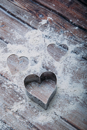 Heart shaped cookie cutter on the kitchen table and flour. Valentine's Day concept. Vertical Imageの写真素材