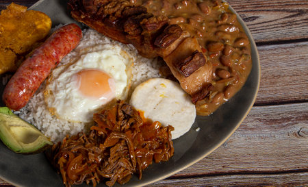 Paisa tray, typical dish of Colombia. It consists of chicharrÃ³n (fried pork belly), black pudding, sausage, arepa, beans, fried banana, avocado egg and riceの写真素材