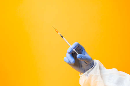 Laboratory hand in medical gloves vaccine treatment research on a yellow background