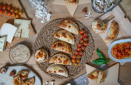 Variety of Argentine homemade empanadas and their ingredients on the wooden table.