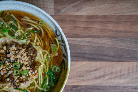 Dandan noodles with minced pork and peanuts on wooden background with space for textの写真素材