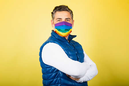 Portrait of man with gay pride mask on a yellow backgroundの写真素材