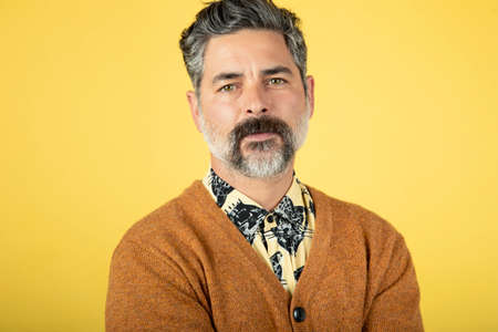Photo of a mature man, isolated on a yellow wall backgroundの写真素材