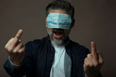Angry man with eye mask showing middle finger gesture in protest.の写真素材