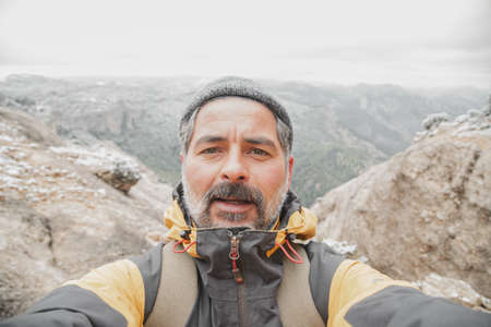 Image of a man doing selfie on top of the mountain looking at camera.の写真素材
