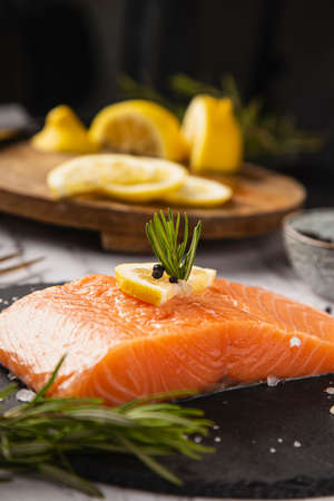 Salmon fillet with lemon and rosemary on the tableの写真素材