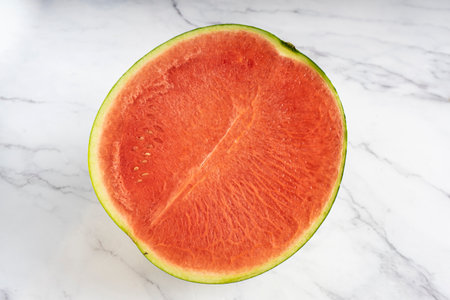 Half watermelon isolated on white marble background