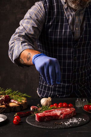 The chef brushes salt over the ready-to-grill beef entrecoteの写真素材