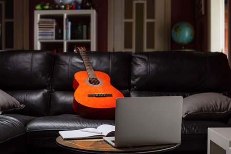 Guitar on the couch at home ready to take guitar lessons online.の写真素材