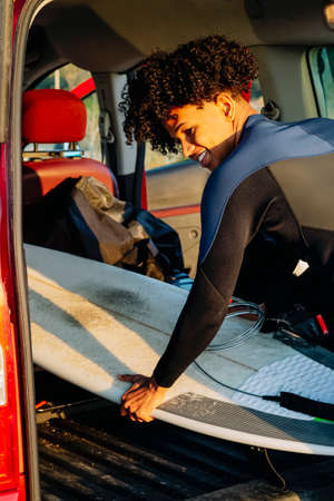 Young African American man with a surfboard in the motorhome