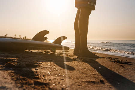 Surfer preparing to surf on the beach at sunrise.の写真素材