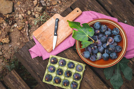 Purple black figs on a rustic wooden picnic tableの写真素材