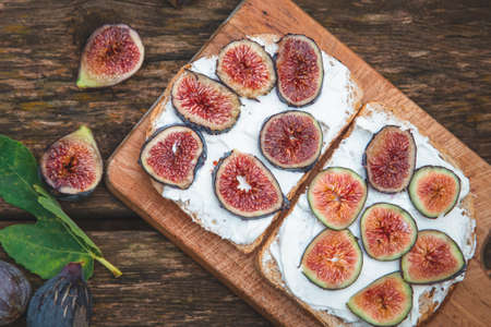 Cream cheese with figs on bread served on wooden boardの写真素材