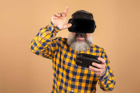 Cheerful man in 3D glasses plays with a joystick on a yellow backgroundの写真素材