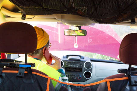 Man inside the cabin of the damaged vehicle talking on the phone with roadside assistance