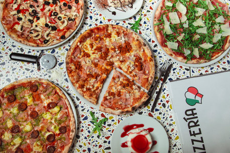 Pizza dinner. Flat lay of various types of Italian pizza and desserts on restaurant table, top view, wide composition.の写真素材