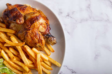 Grilled chicken with french fries and salad on a marble table. Top view with copy space.の写真素材