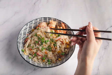female hand with chopstick close-up eating asian food, top view.の写真素材