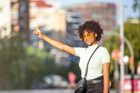Latin American young woman trying to stop a taxi in the cityの写真素材