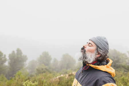 Relaxed mountaineer breathing fresh air high in the mountains with fog in the backgroundの写真素材