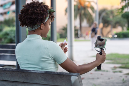Afro young man streaming makeup tips for his followers on social media.の写真素材