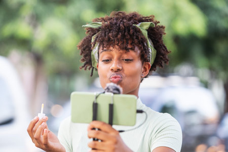 Young afro man recording a makeup tutorial to share on social networks.の写真素材