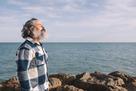 Side view portrait of a bearded man breathing fresh air on the beachの写真素材