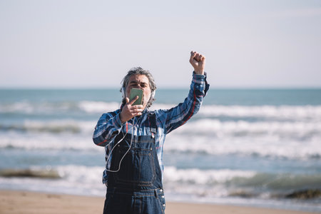 Middle-aged man listening to music with headphones by the sea