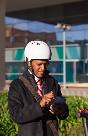 cheerful Latino businessman smiling while using smartphone