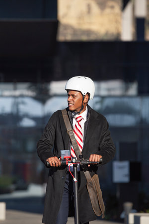 Young businessman in a suit riding an electric scooter at a business meeting. Eco transport concept