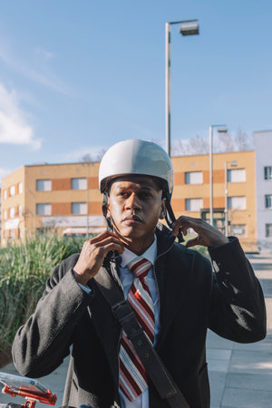 Young businessman putting on helmet riding an electric scooterの写真素材
