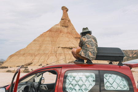 Traveler sitting on top of a van taking photos of the rocky landscape of the Navarra desertの写真素材