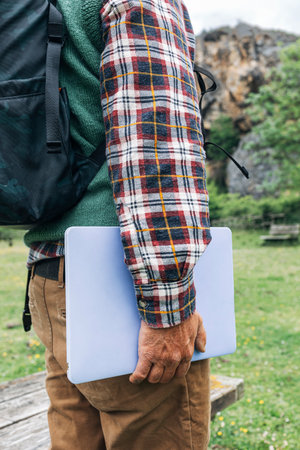 Close up of freelance male traveler with laptop in nature, side view.
