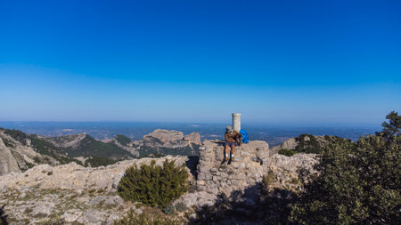 a hiker on the top of a mountain with his pet. mountaineer contemplating the landscape from a mountain peak. outdoor activities. travel with dogの写真素材